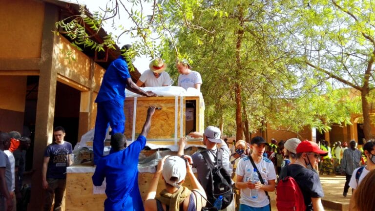 Menschen packen Solarmodule einer PV-Anlage aus, für die Stromversorgung einer Bäckerei in Burkina Faso, als Teil eines Hilfsprojekts, an dem autarxia beteiligt war.